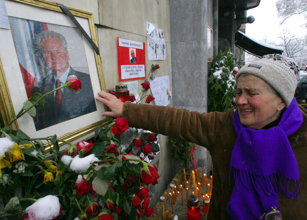 A woman cries as she touches a photo showing late Serbian and Yugoslav president Slobodan Milosevic, in front of his Socialist party headquarters in downtown Belgrade, Monday, March 13 2006. A Dutch toxicologist confirmed Monday he found traces of an unprescribed drug in a blood sample taken from former Yugoslav President Slobodan Milosevic earlier this year, and a legal aide to Slobodan Milosevic says he will be buried in Belgrade. Milosevic died in his prison prison cell in The Hague, on Saturday, March 11 2006. (AP Photo/Srdjan Ilic)